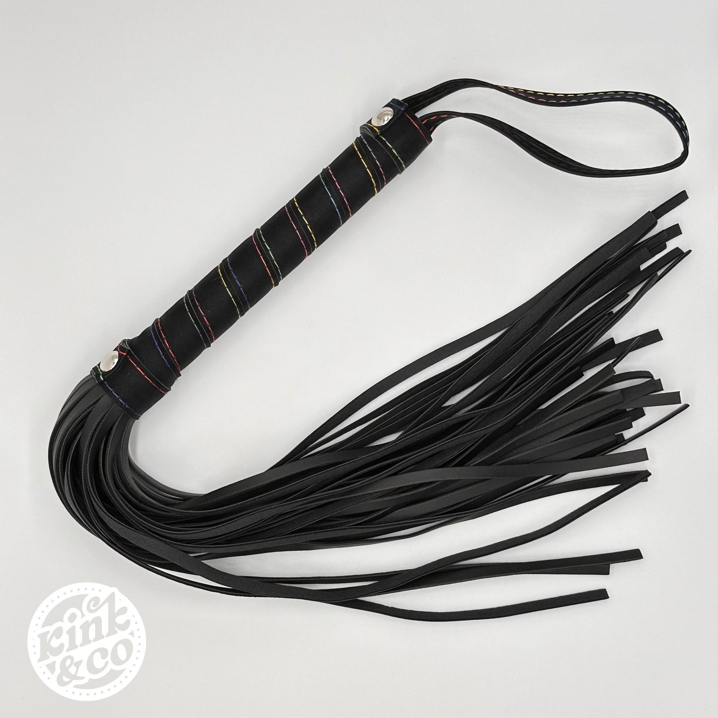 Top view of Black faux leather BDSM flogging whip with rainbow stitching spiral on the handle. Grey background with kink and co logo in the top left