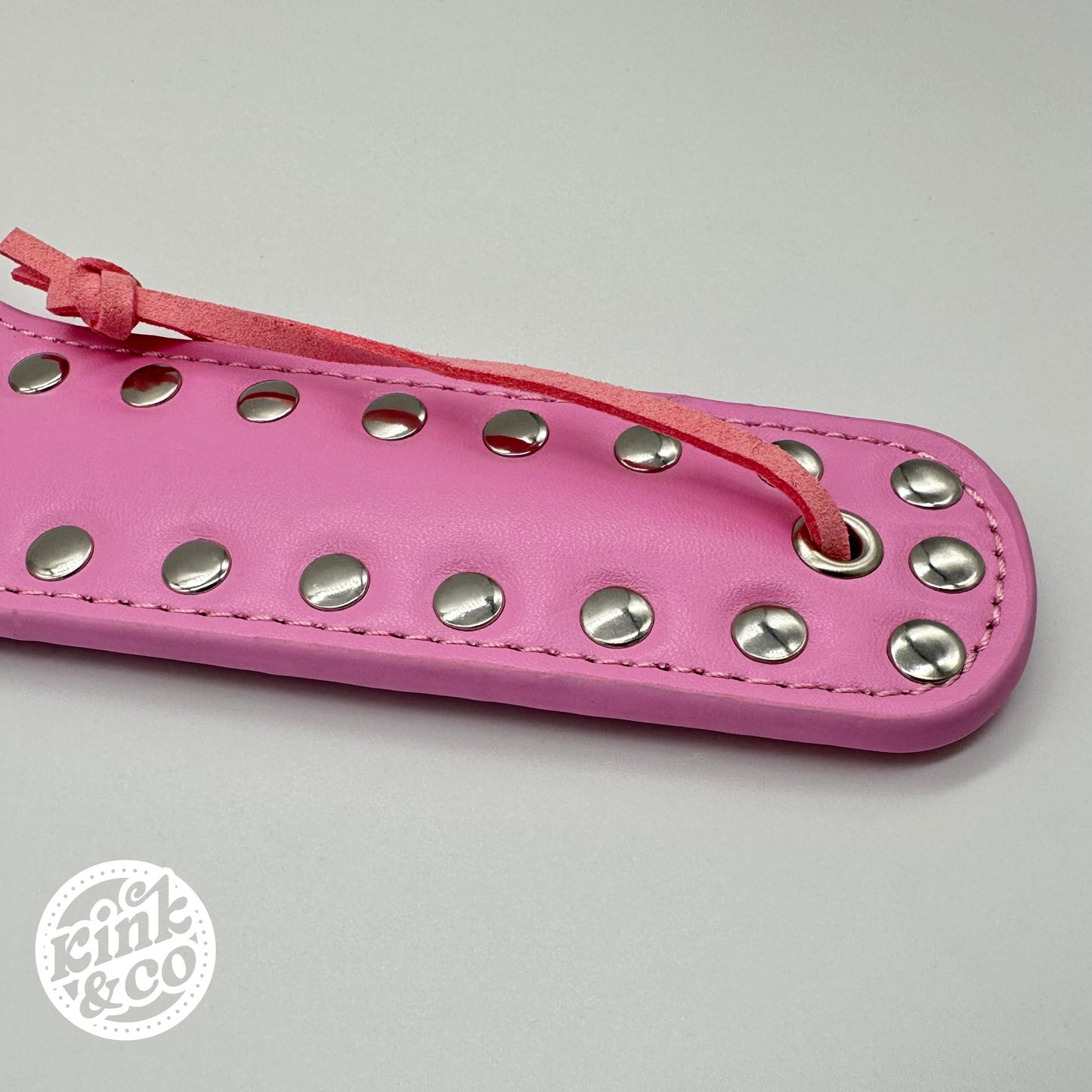 Rosa Spankingpaddel aus Kunstleder mit Herzmotiv und Nieten